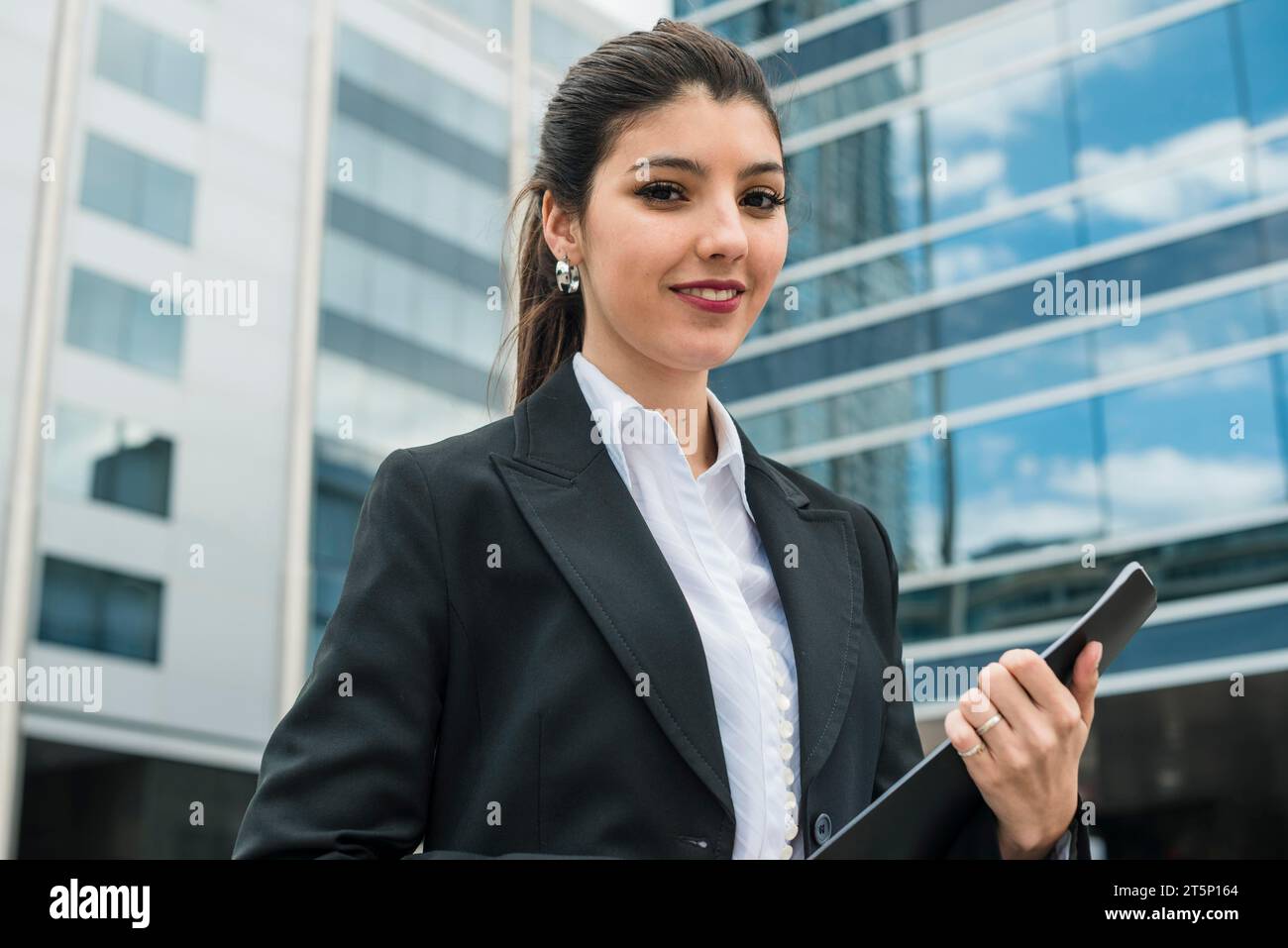 Ritratto giovane donna d'affari sorridente in piedi davanti all'edificio Foto Stock