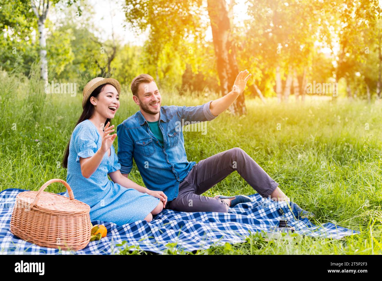 Giovani coppie felici che salutano la natura del picnic sorridente Foto Stock