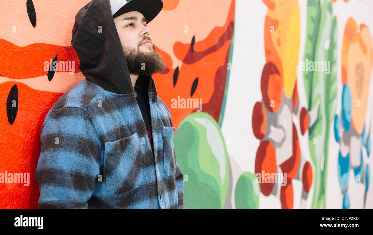 Barba in piedi davanti a una parete di graffiti colorata Foto Stock