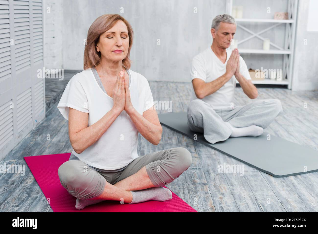 Coppia senior concentrata che esegue yoga a casa Foto Stock