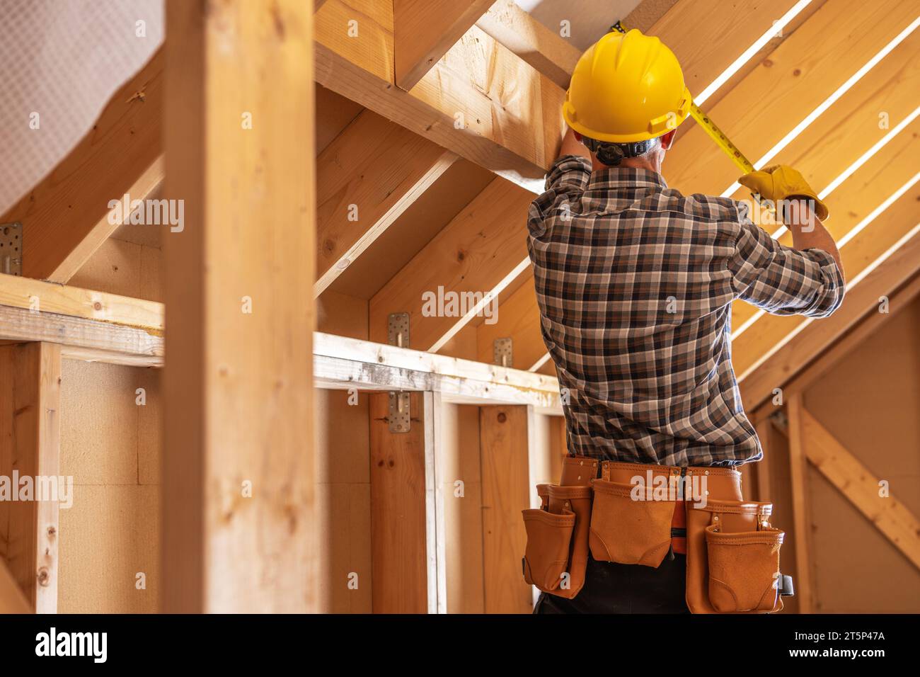 Operaio edile che effettua misurazioni all'interno di strutture in legno. Tema cantiere. Foto Stock
