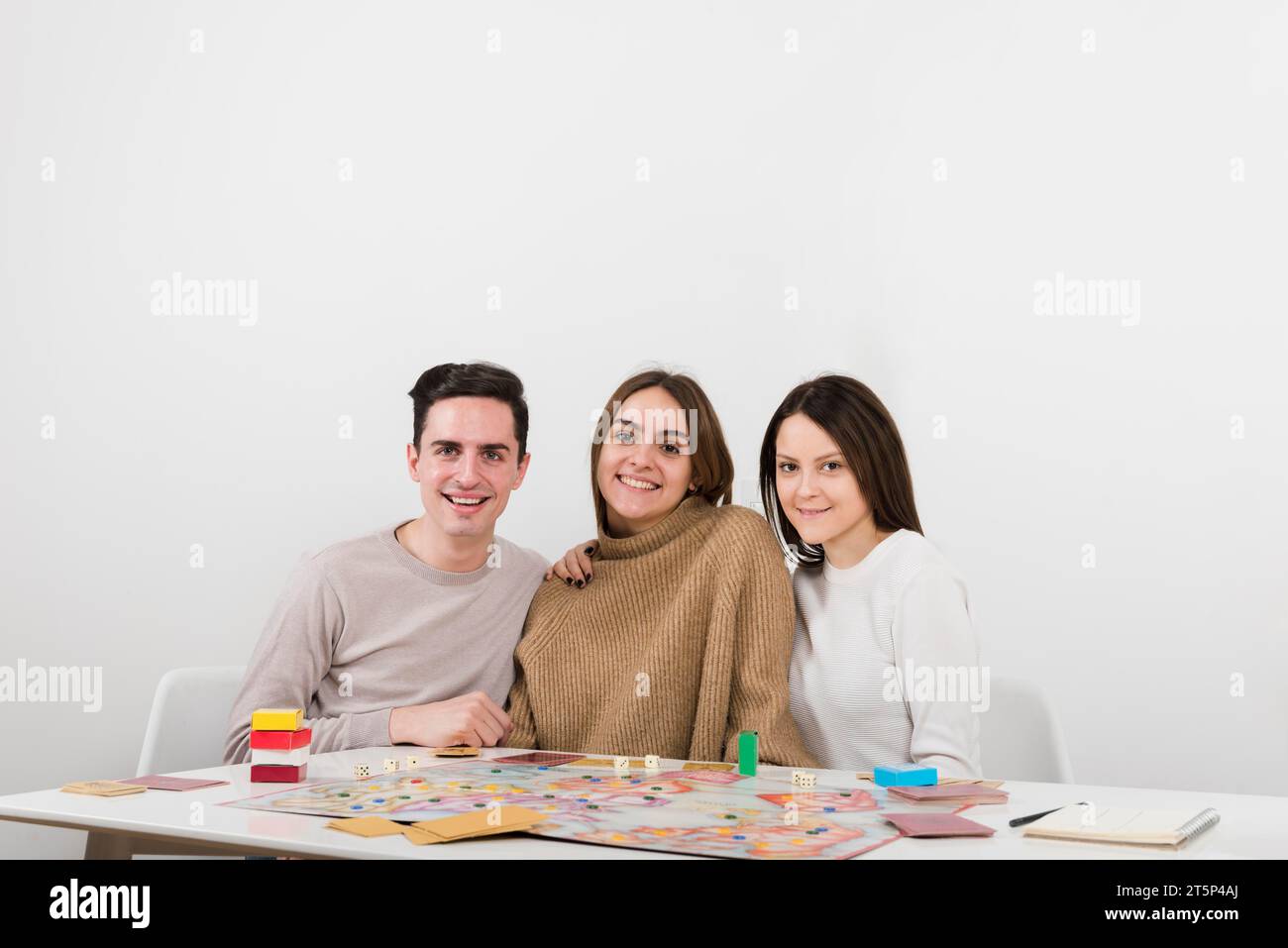 Vista frontale degli amici sorridenti che giocano a un gioco da tavolo Foto Stock