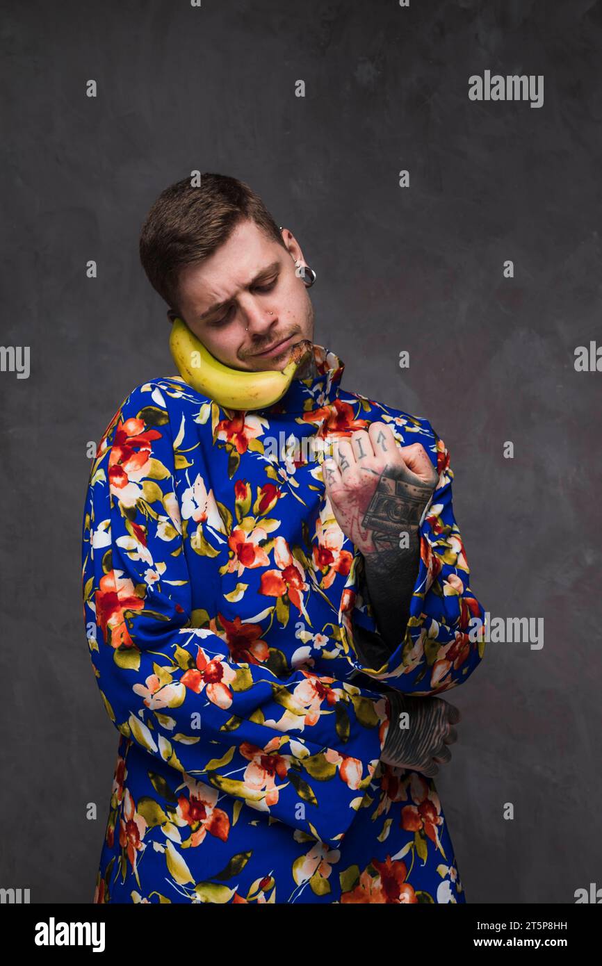 Simpatico sorridente che tiene banana invece al telefono Foto Stock