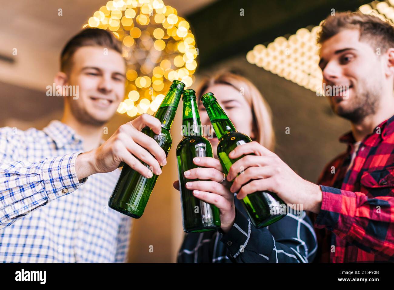 Vista dall'angolo basso Happy Friends che bevono una bottiglia di birra Foto Stock