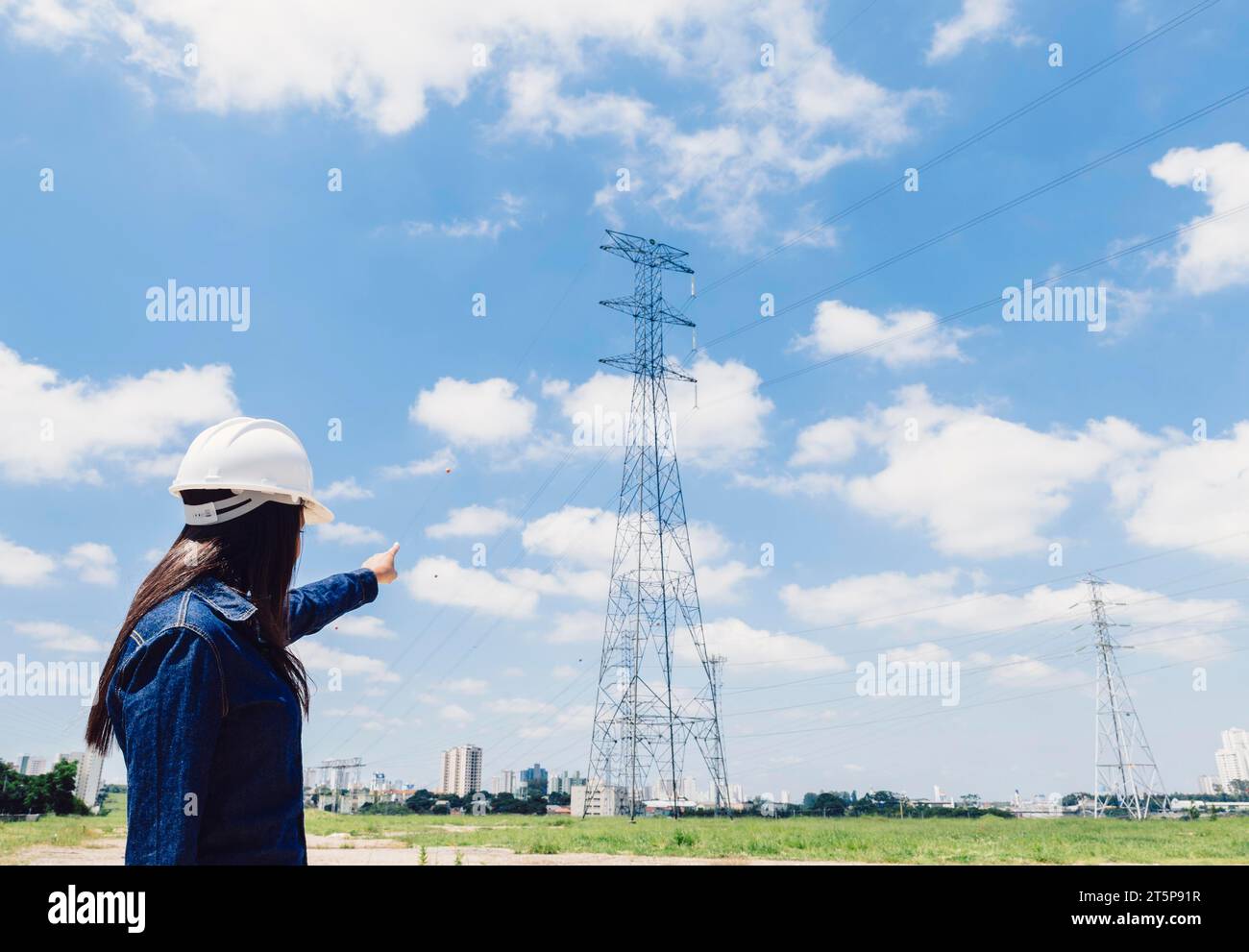 Elmetto di sicurezza Lady che indica la linea ad alta tensione Foto Stock