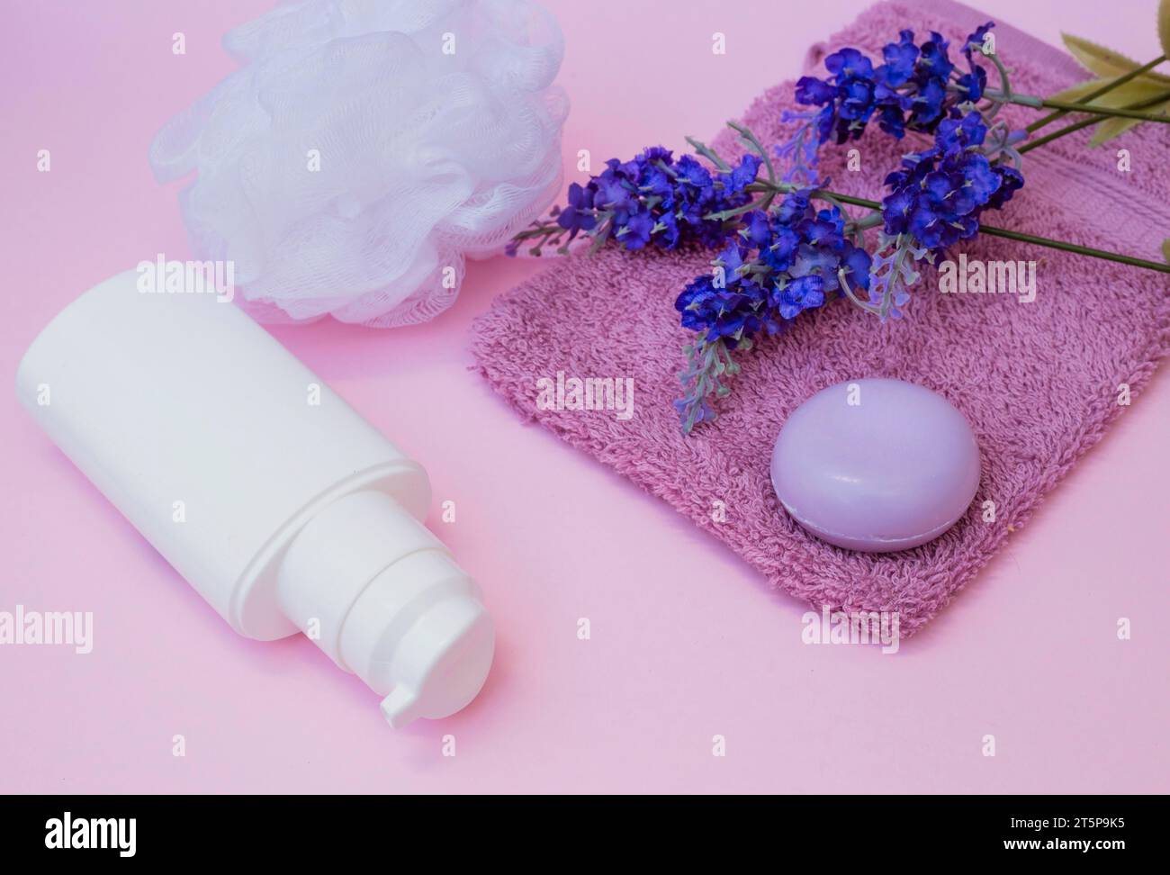 Sapone asciugamano loofah fiore di lavanda bottiglia cosmetica sfondo rosa Foto Stock