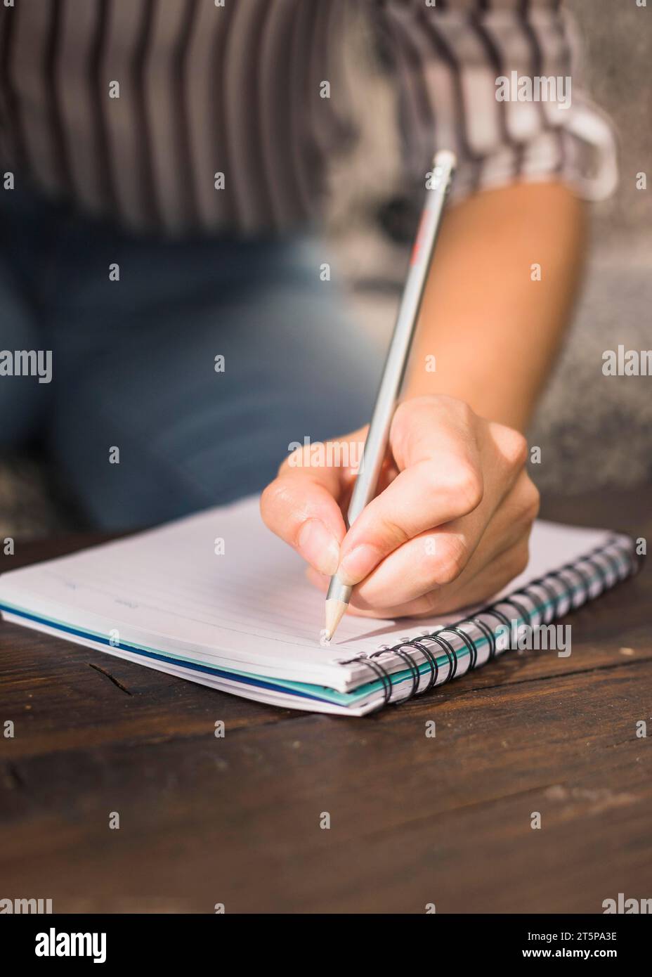 Donna che scrive con taccuino a spirale a matita tavolo in legno Foto Stock