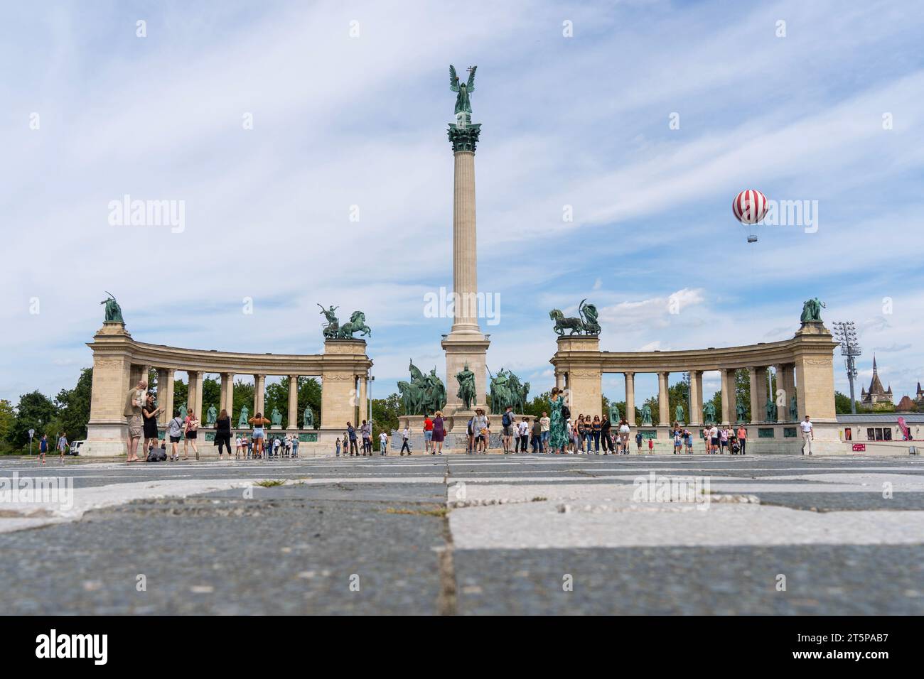 La storica Piazza degli Eroi (Hosok Tere) con i turisti che scattano foto nell'estate 2023. Sullo sfondo, un palloncino rosso e bianco Foto Stock