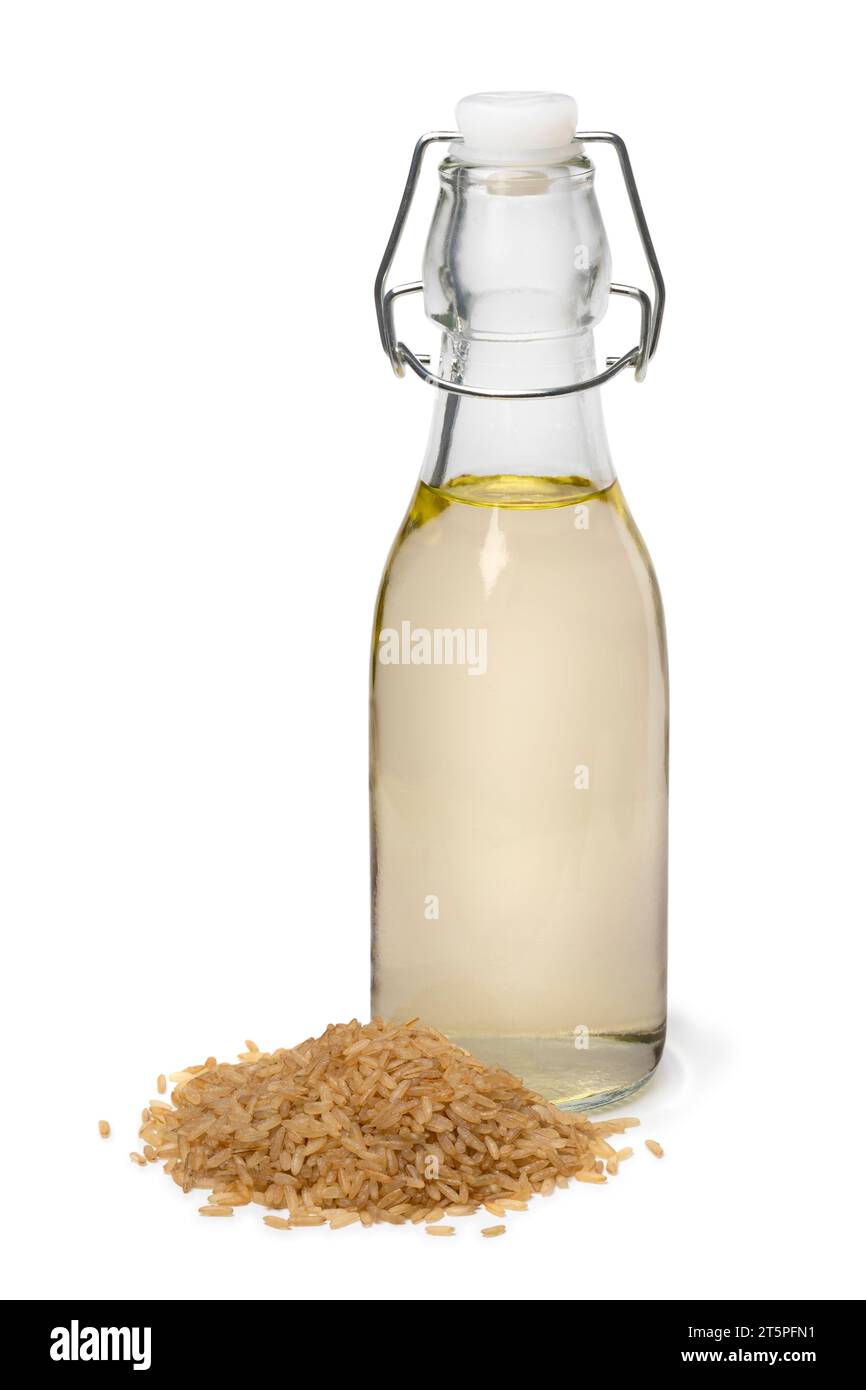 Bottiglia di vetro con aceto di riso integrale e un mucchio di riso integrale davanti isolato su sfondo bianco da vicino Foto Stock