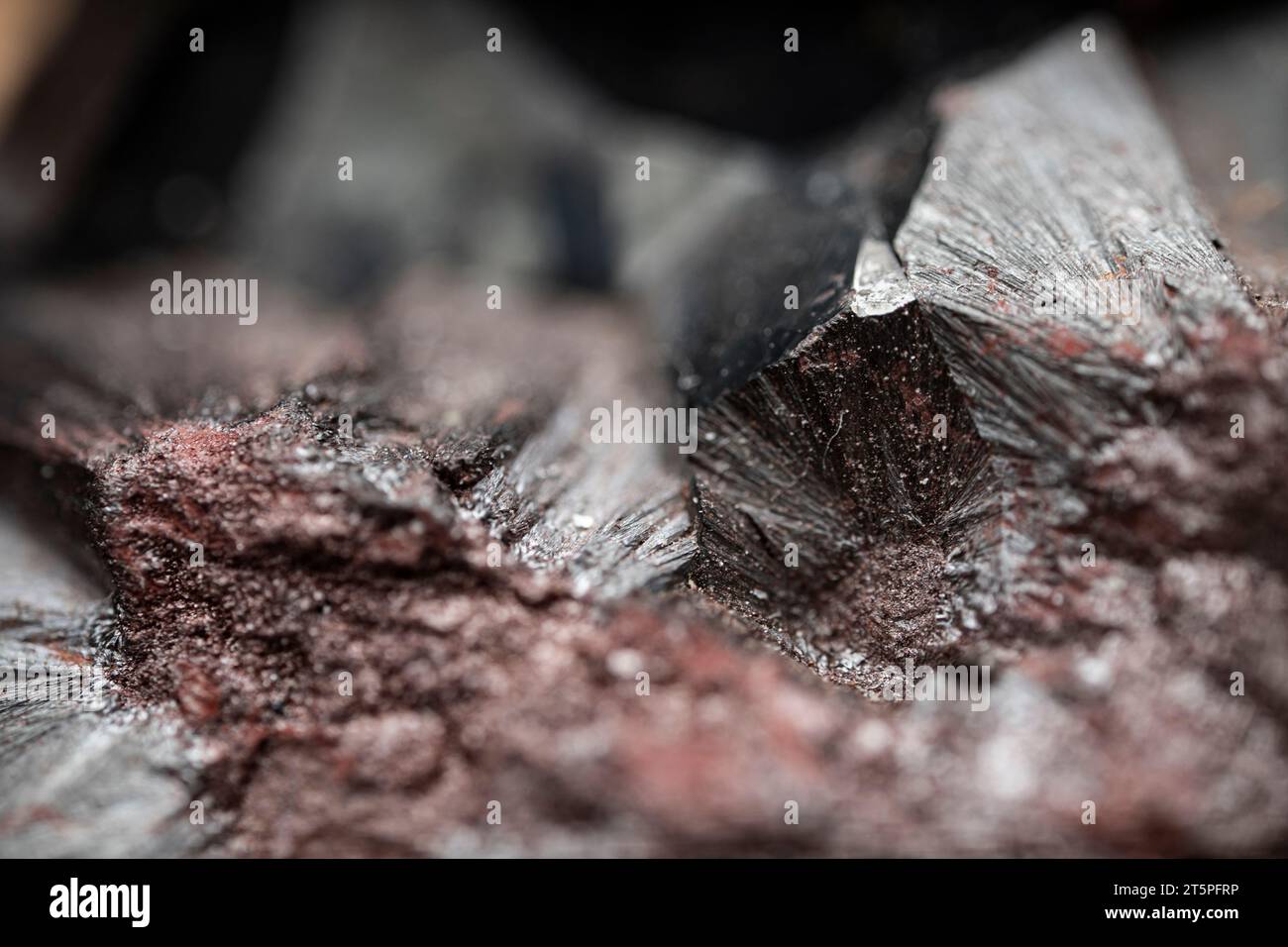 Struttura in metallo. Primo piano di una pietra ematitica grezza. Minerale lucido con un motivo astratto. Foto Stock
