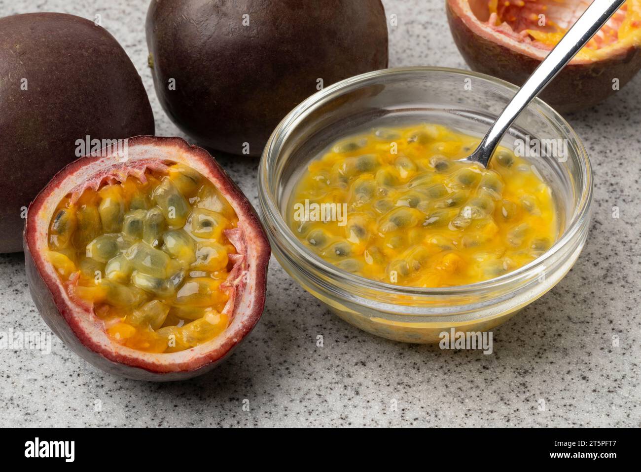 Frutto della passione tropicale fresco a metà e una ciotola di vetro con succo di frutta della passione e semi da vicino Foto Stock
