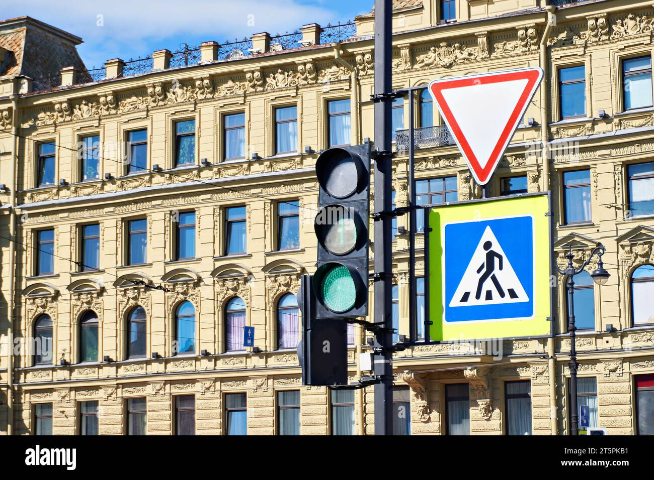 Semaforo e segnali stradali sullo sfondo di un vecchio edificio cittadino Foto Stock