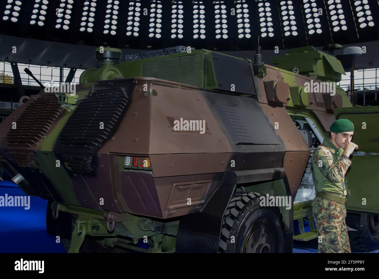 Soldato in uniforme mimetica armato di equipaggiamento militare, accanto a un veicolo corazzato, utilizzando attrezzature di sorveglianza militari Foto Stock