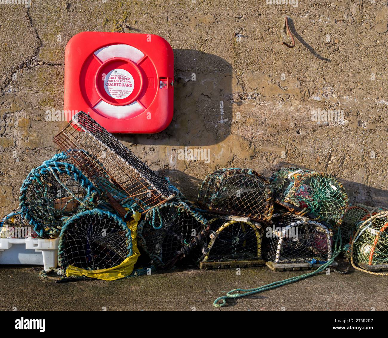 6 novembre 2023. Findochty, Moray, Scozia. Si tratta di una boa di salvataggio fornita dall'HM Coastguard sul muro di un molo accanto ad alcuni crelli da pesca. Foto Stock