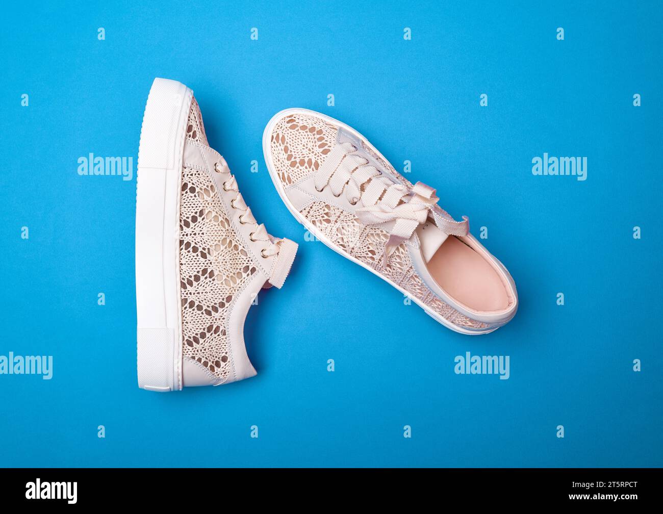 Un paio di comode sneaker in maglia beige con suola in gomma spessa bianca su sfondo blu brillante. Fotografia di moda Foto Stock