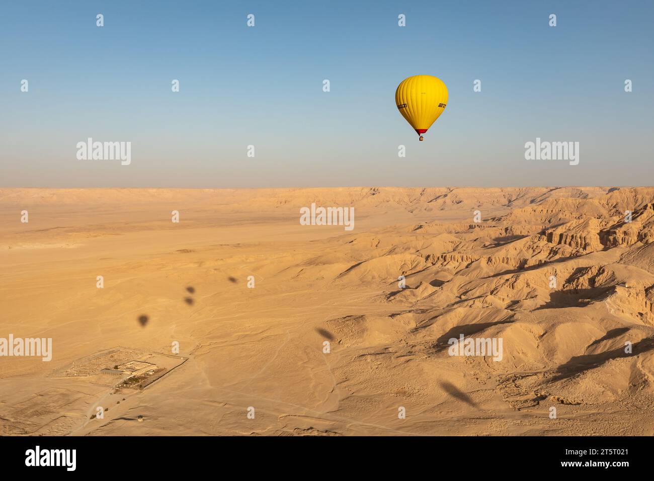 La mongolfiera si innalza nel cielo blu sopra il deserto e le antiche rovine della Valle dei Re Foto Stock