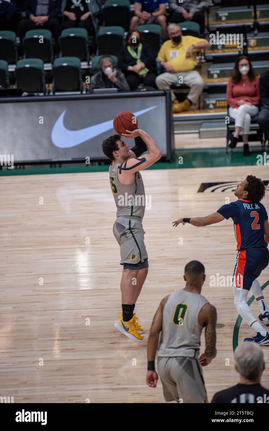 Giocatore di pallacanestro universitario che esegue un salto controverso durante l'azione di gioco NCAA, catturato con dettagli nitidi, estensione completa e dinamica arena al coperto Foto Stock