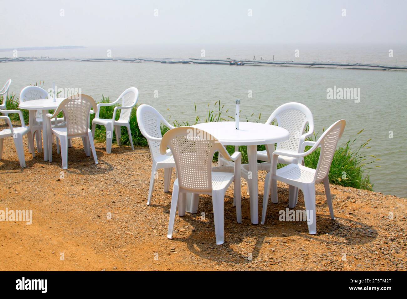 Tavoli e sedie di plastica bianca sulla diga Foto Stock