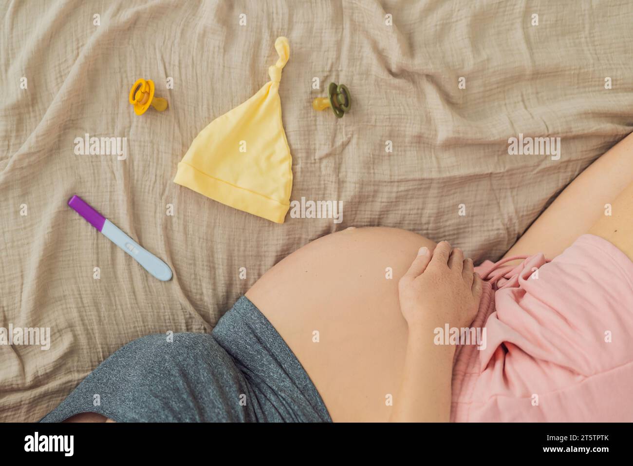 Una composizione di caratteristiche essenziali della gravidanza: Un test di gravidanza positivo, un'immagine ecografica, un piccolo succhietto e un cappuccio morbido per il bambino, che incarna il Foto Stock