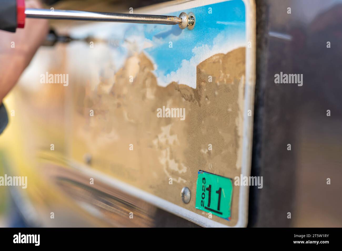Utilizzare un cacciavite per rimuovere e sostituire la targa posteriore del veicolo. Foto Stock