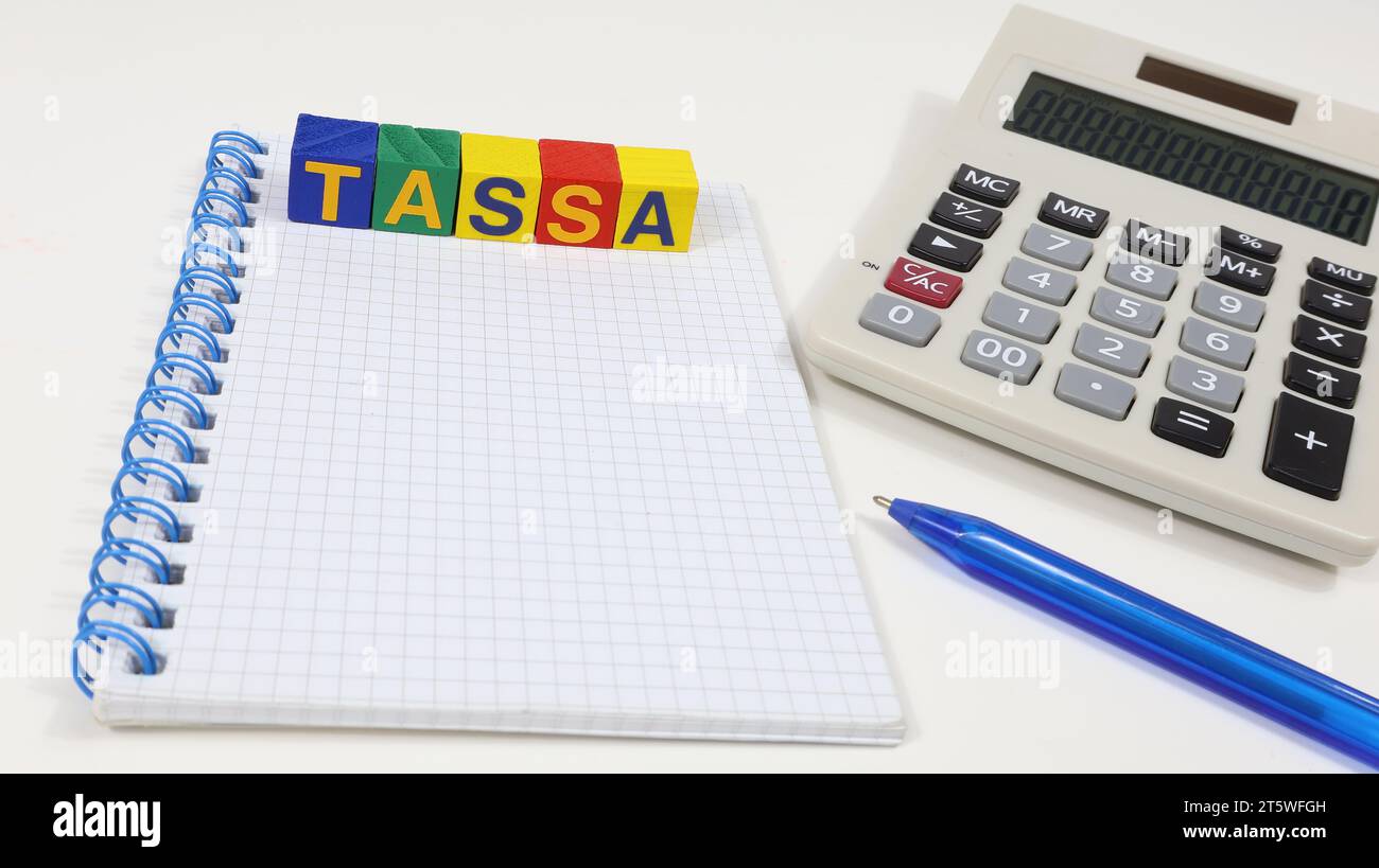 Parola singola "TASSA" su blocco di legno. Tasse sul concetto, riforma del governo italiano. Notebook sul tavolo Foto Stock