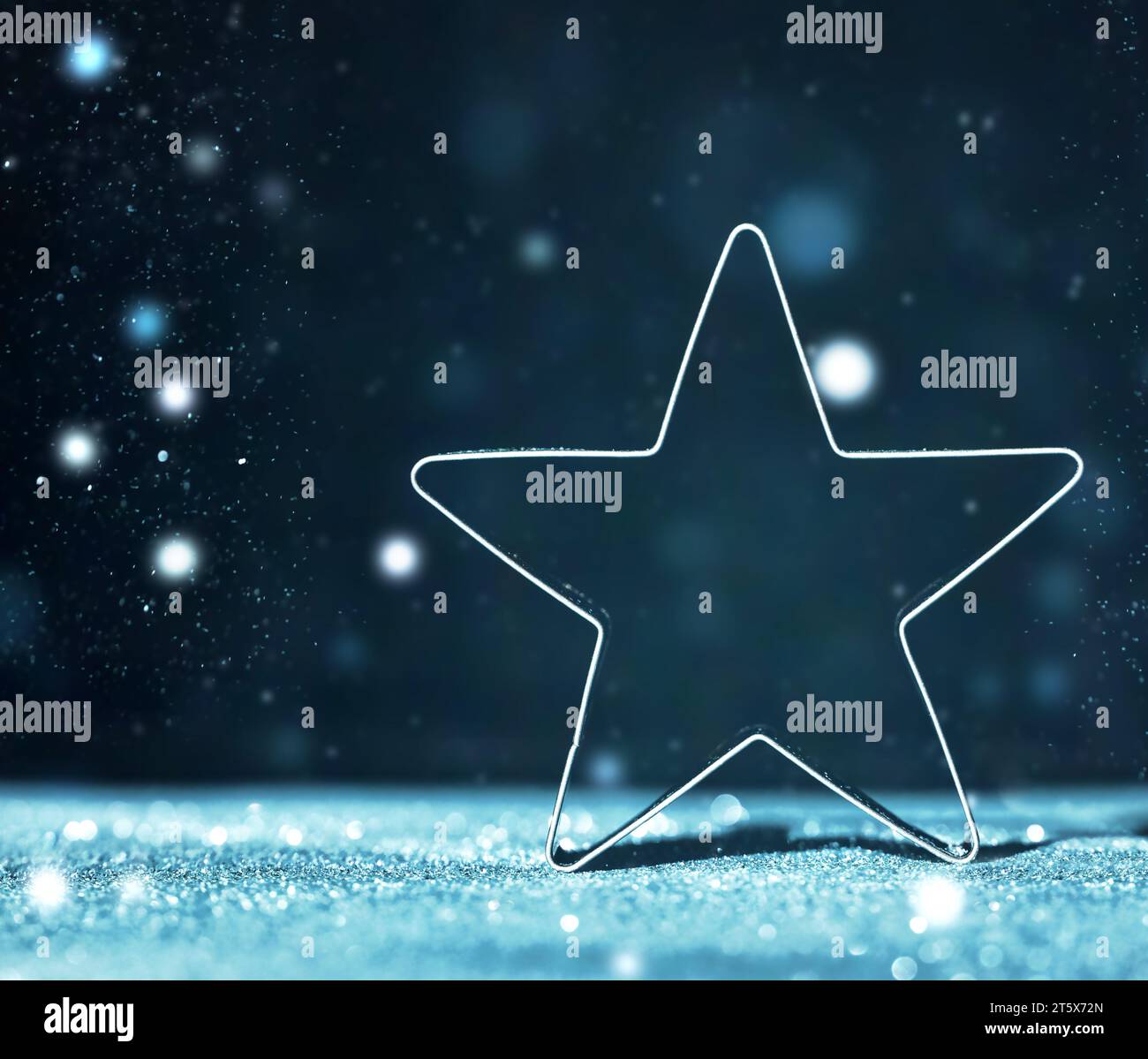 Sparkling Christmas Star su sfondo bokeh scuro sfocato. Decorazioni natalizie con luci blu sfocate glitter Foto Stock