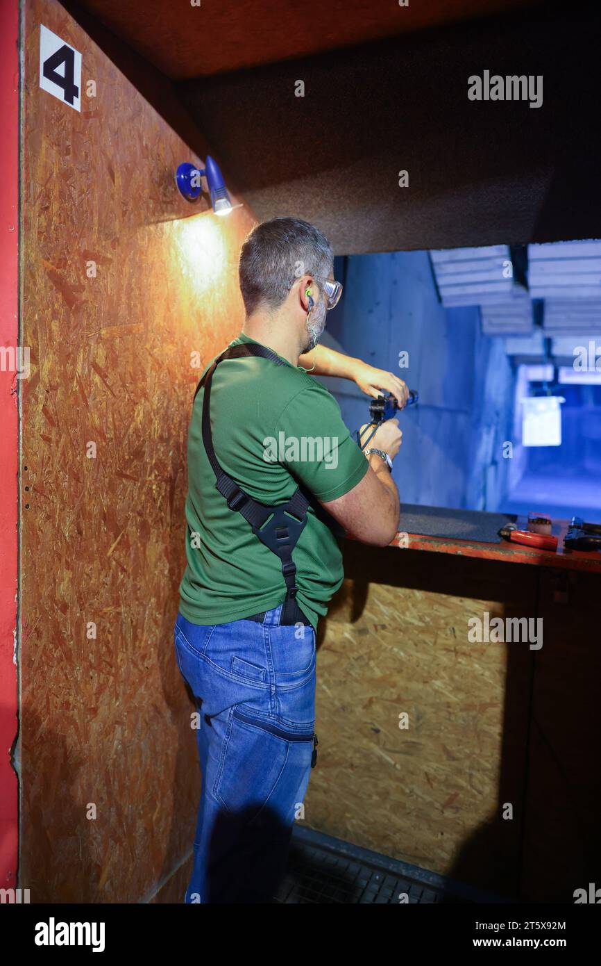 Vista dettagliata del tiratore tenendo la pistola e la formazione di tiro tattico, vicino. Tiro a segno Foto Stock