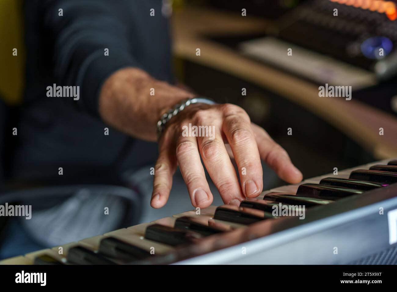 Primo piano delle mani di un musicista che suona una tastiera elettronica concentrata su dita e tasti, catturando l'essenza della creazione musicale. Foto Stock