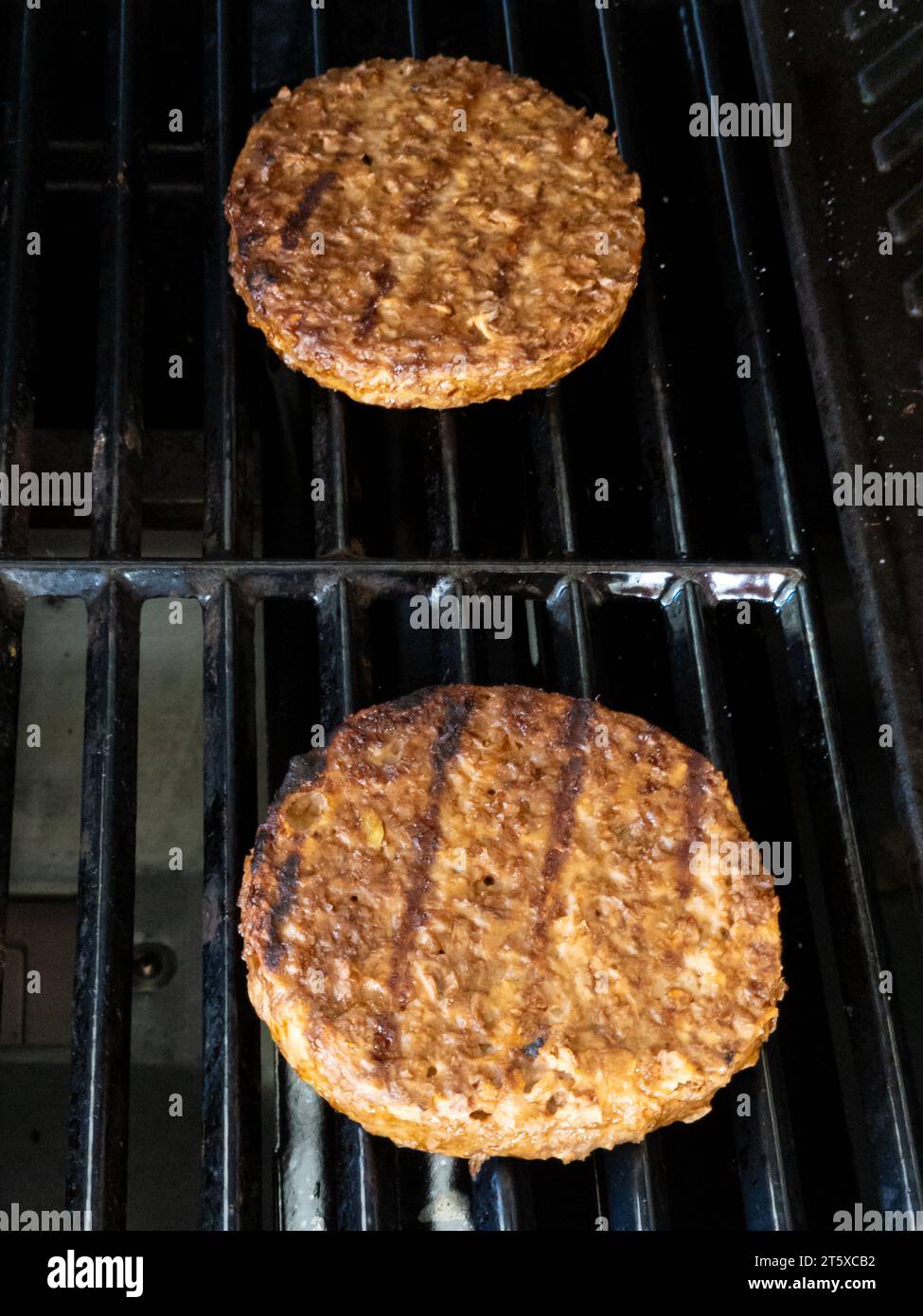 Due succulenti hamburger vegani grigliati sulla piastra per barbecue Foto Stock