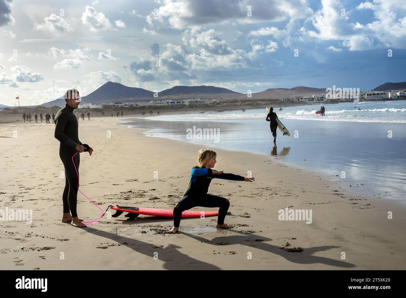 Spagna, Lanzarote, Caleta de Famara: Il padre insegna al figlio a fare surf sulla spiaggia di Famara Foto Stock