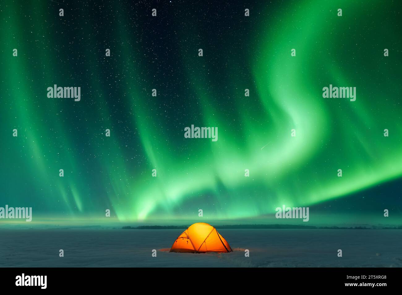 Tenda arancione illuminata dall'interno sullo sfondo dell'incredibile cielo con l'aurora boreale. Aurora boreale in campo invernale Foto Stock