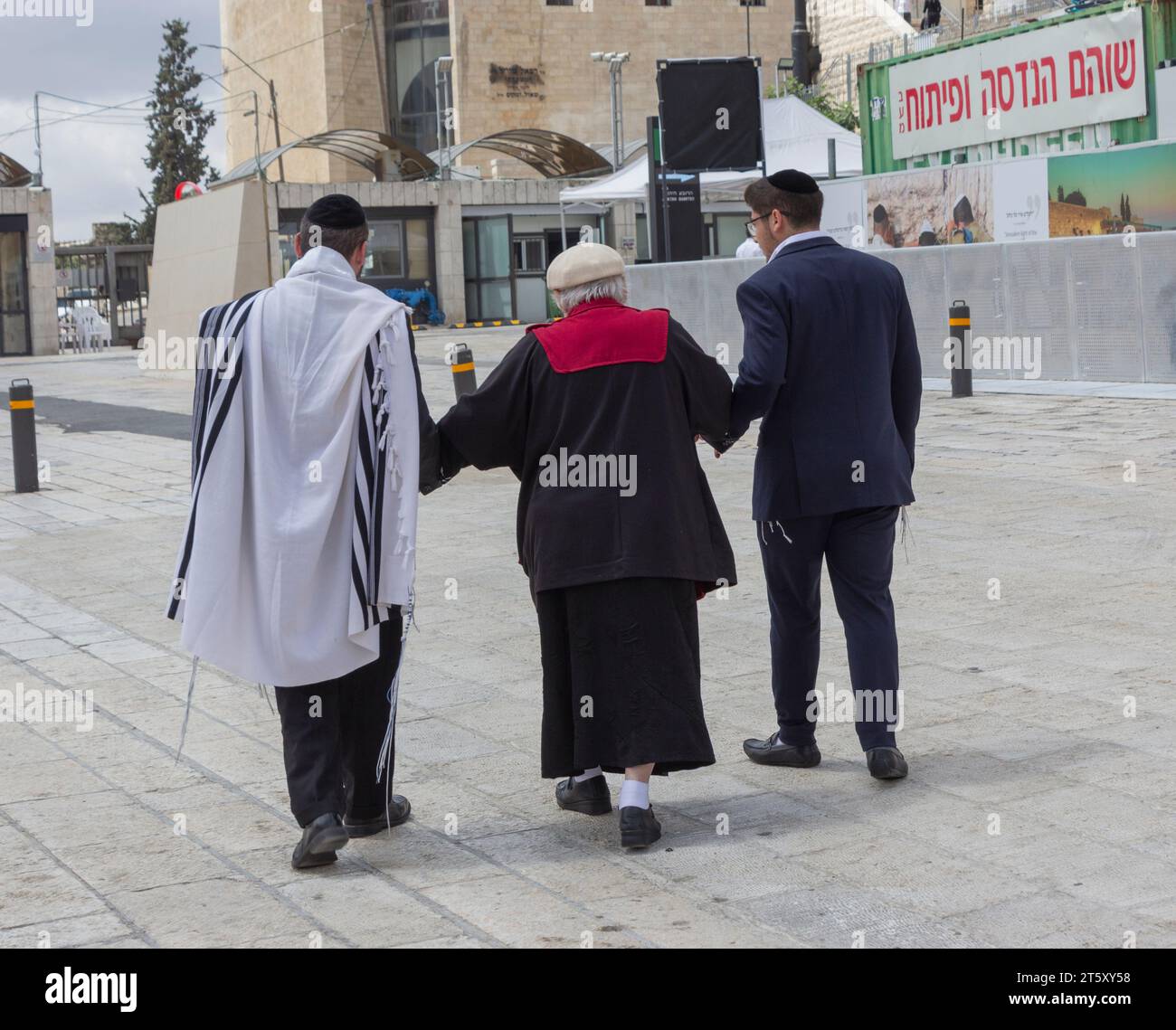 Gli ebrei ortodossi aiutano un uomo anziano dopo aver lasciato il muro del pianto, Gerusalemme, Israele. Foto Stock