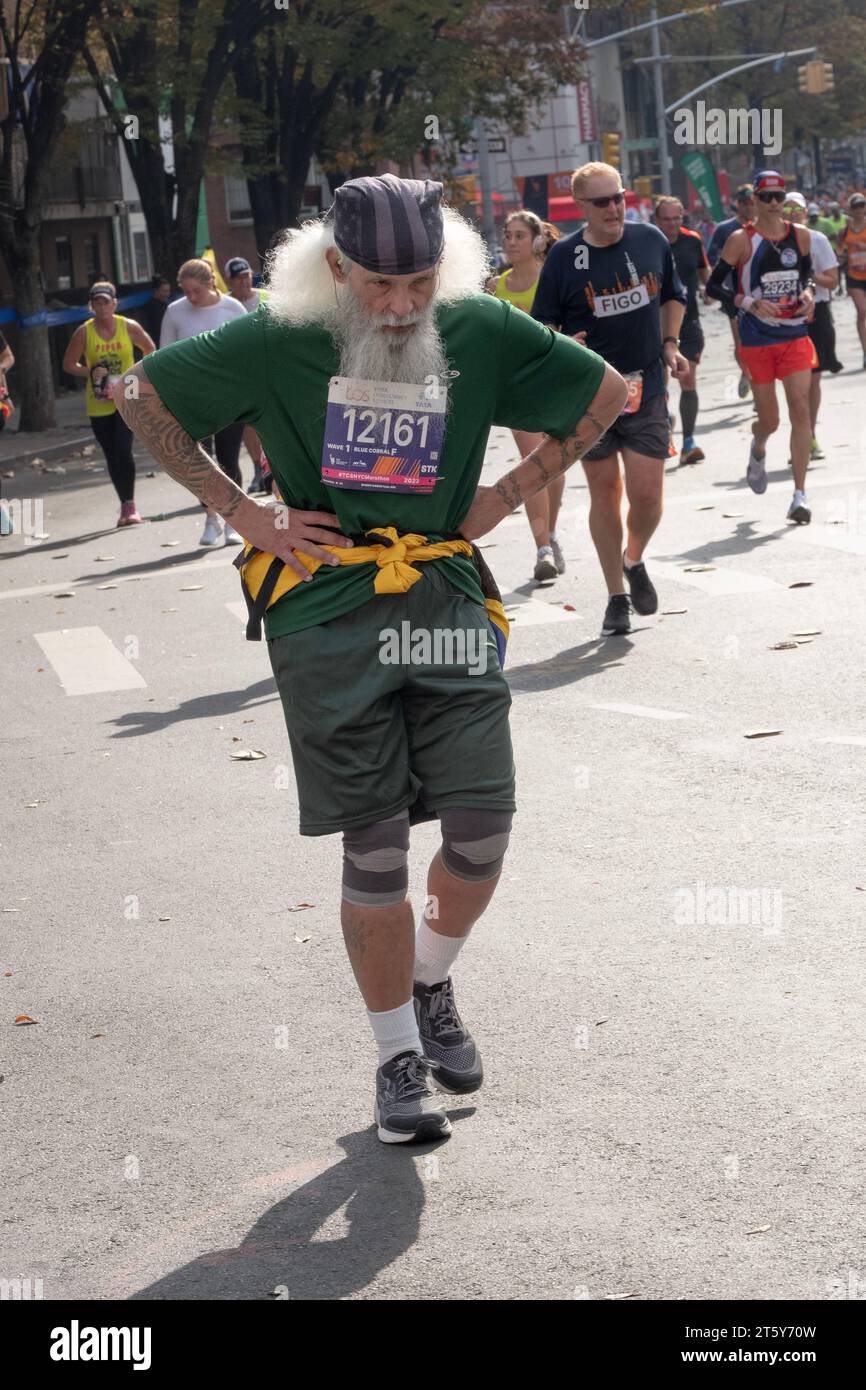 Un corridore più vecchio con i capelli grandi e la barba grigia sembra battere dopo appena 16 chilometri dalla Maratona di New York. A Williamsburg, Brooklyn, New York. Foto Stock