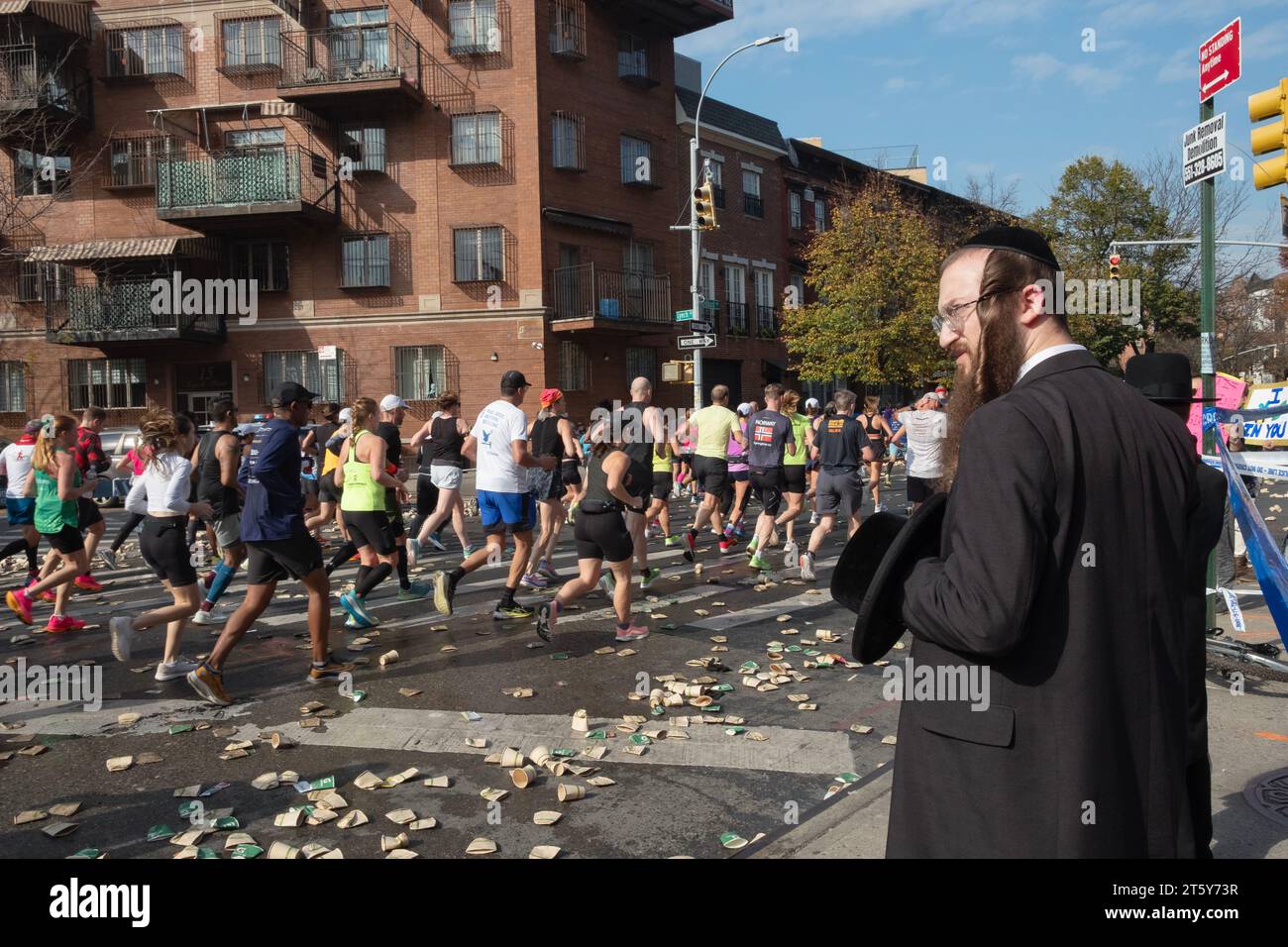 Alla 16 miglia della Maratona di New York, un ebreo ortodosso aspetta uno spazio tra i corridori per attraversare Bedford Ave. A Williamsburg, Brooklyn, New York. Foto Stock