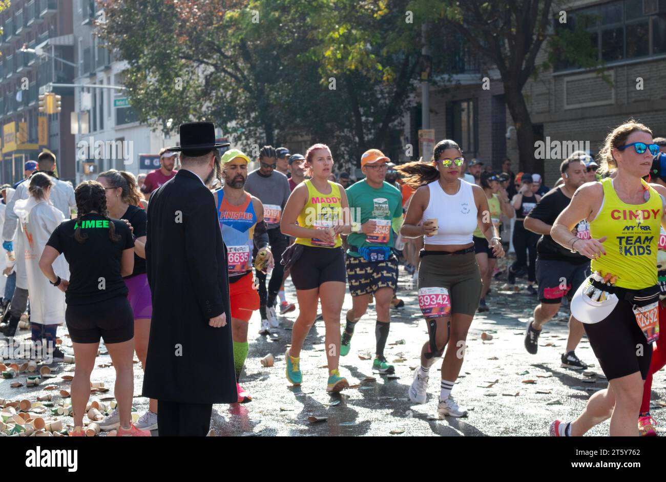 Alla 16 miglia della Maratona di New York, un ebreo ortodosso aspetta uno spazio tra i corridori per attraversare Bedford Ave. A Williamsburg, Brooklyn, New York. Foto Stock