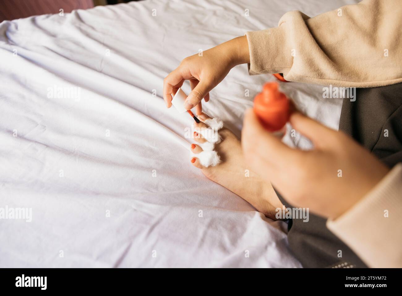 Primo piano di una giovane donna che fa pedicure a letto a casa Foto Stock