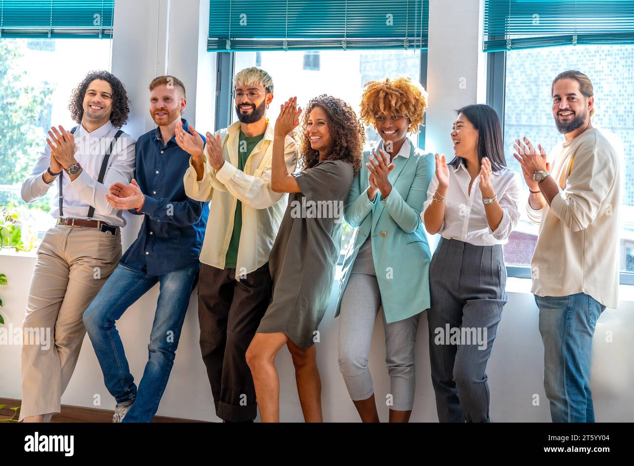 Ritratto di un allegro team di giovani e multirazziali cowokers che festeggiano mentre applaudono Foto Stock