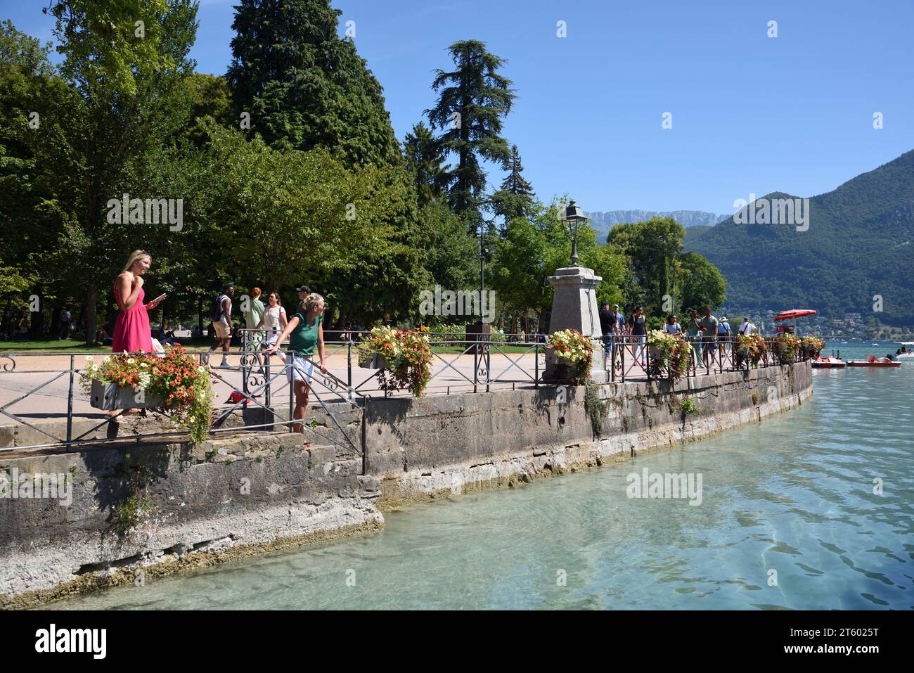 Turisti che camminano lungo il Quai Napoléon nei Jardins de l'Europe sul lungolago o sul lungofiume del lago Annecy alta Savoia Francia Foto Stock
