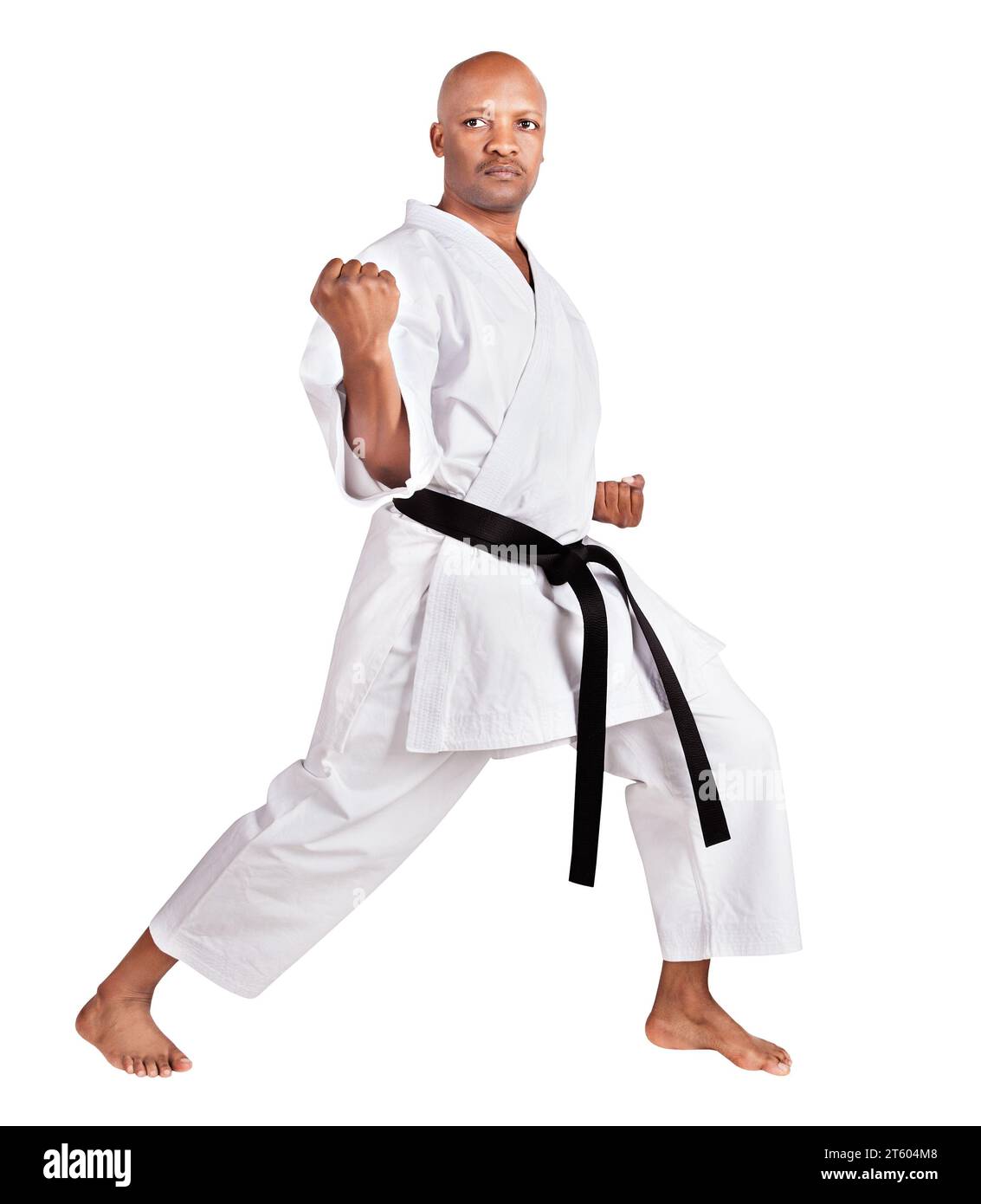 un karate afroamericano in una posizione kumite, che esercita il suo kata, in uniforme kimono bianca con cintura Foto Stock