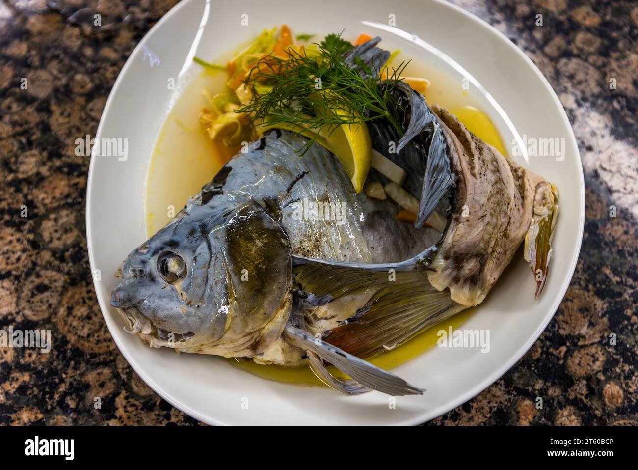 Metà di un "Karpfen blau" ("carpa blu") è servita nel suo brodo con verdure e limone. Il piatto è tradizionalmente accompagnato da patate al prezzemolo. Casa per ospiti St. Joseph, Monastero di Waldsassen, Waldsassen, Baviera, Germania. Foto Stock