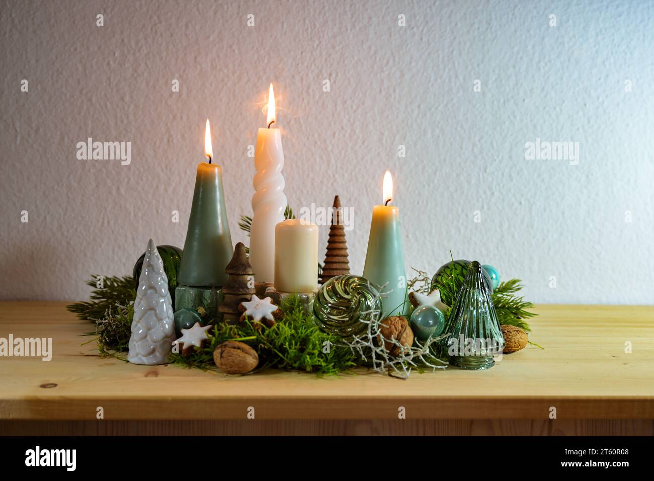 Terzo Avvento, decorazione con quattro diverse candele, tre accese, alcuni muschi, palline di Natale verdi di vetro e stelle di cannella su una tavola di legno Foto Stock