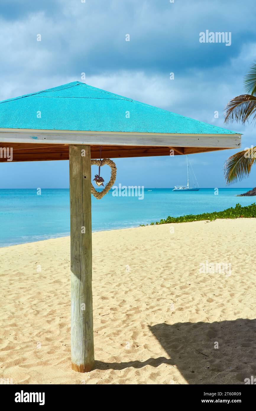 Ombrellone con cuore su una spiaggia di sabbia tropicale con un mare turchese. Foto Stock