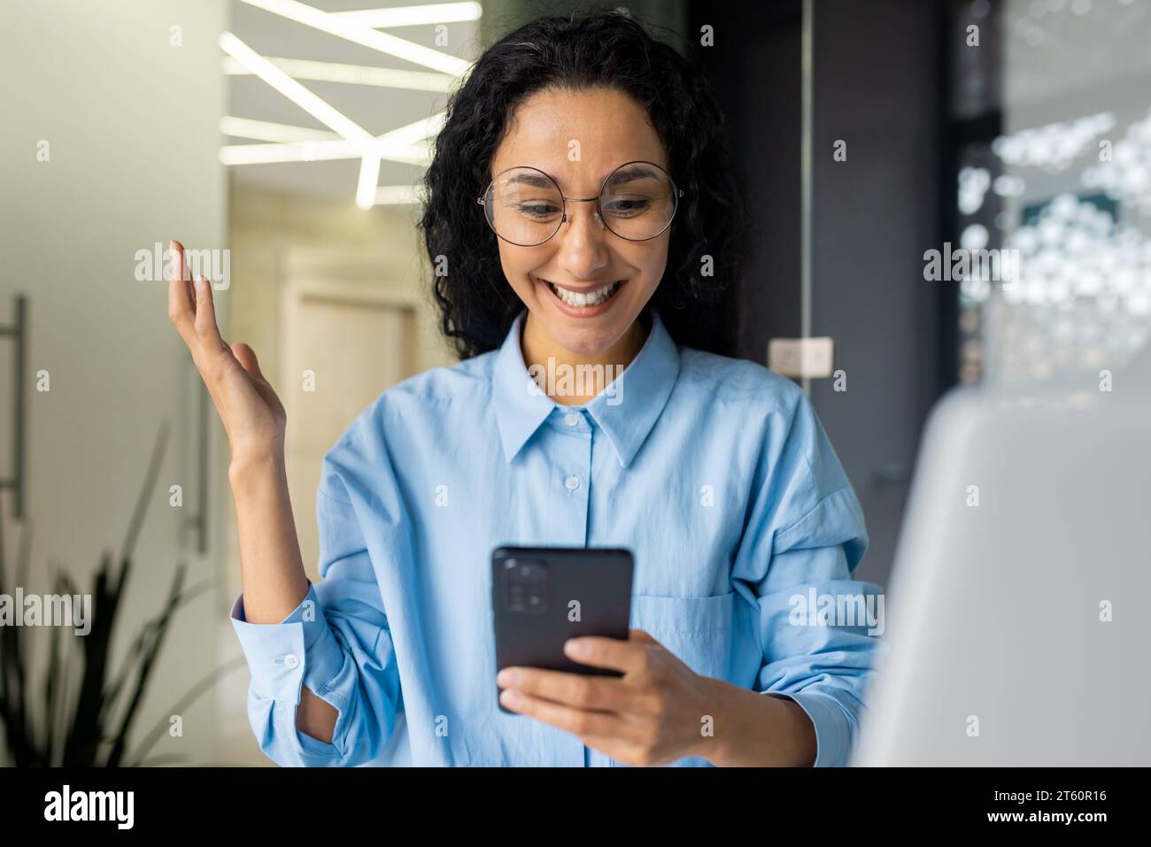 Felice donna ispanica di successo che sorride leggendo la notifica, celebrando il successo della vittoria, donna d'affari ha ricevuto un messaggio online di notizie, tenendo in mano il telefono, utilizzando l'app sullo smartphone. Foto Stock