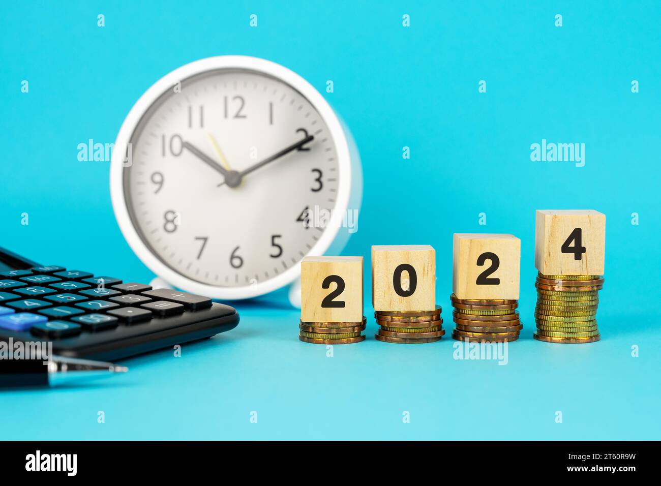 Numero 2024 in cima alle pile di monete su sfondo blu Foto Stock