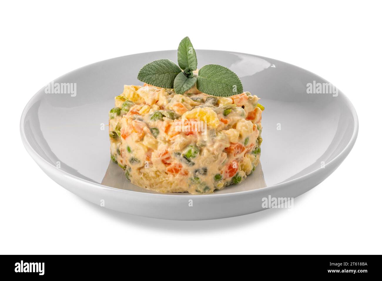 Insalata russa in piatto bianco con foglie di salvia, insalata tipica piemontese italiana a pezzetti di verdure con salsa alla maionese. Isolato su bianco Foto Stock
