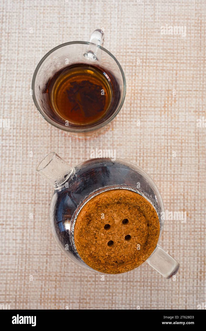Tè nero in una tazza di vetro e teiera di vetro su un tovagliolo dall'alto Foto Stock