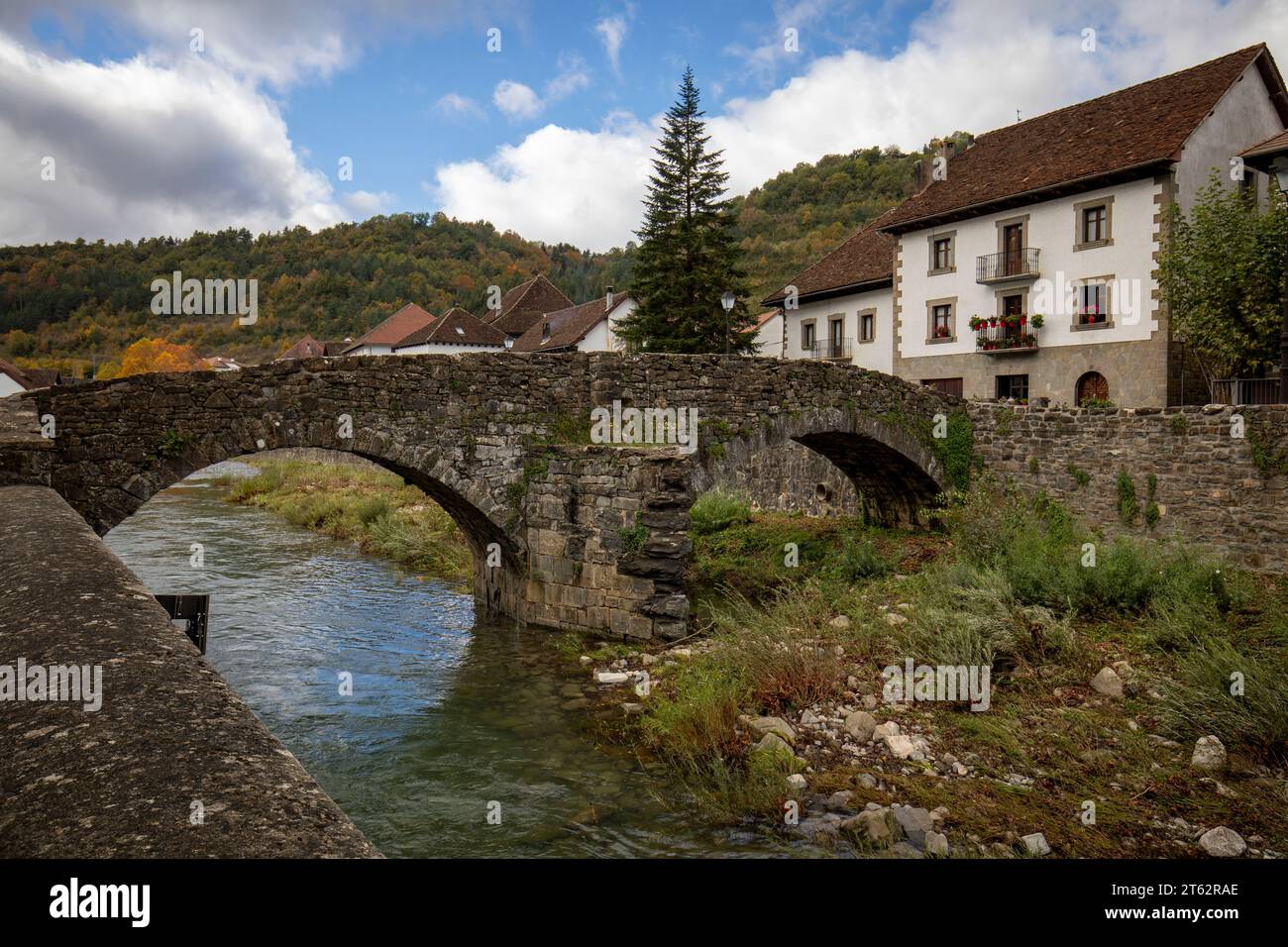 Antico ponte medievale in pietra sul fiume Anduña nel tipico villaggio pireno di Ochagavía in Navarra, Spagna, con luce a mezzogiorno Foto Stock