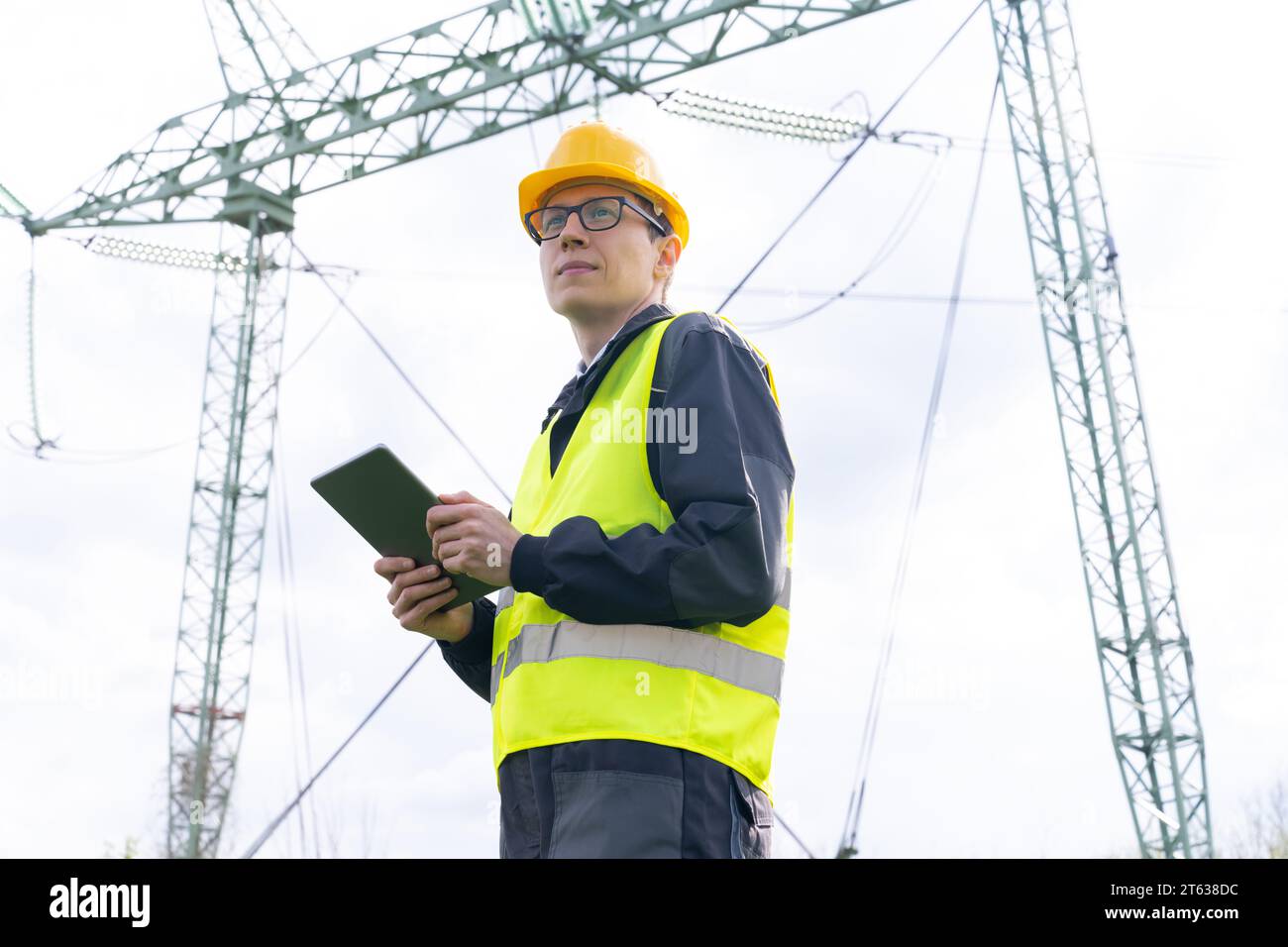 Progettare con un tablet digitale sullo sfondo di una torre della linea elettrica. Foto Stock