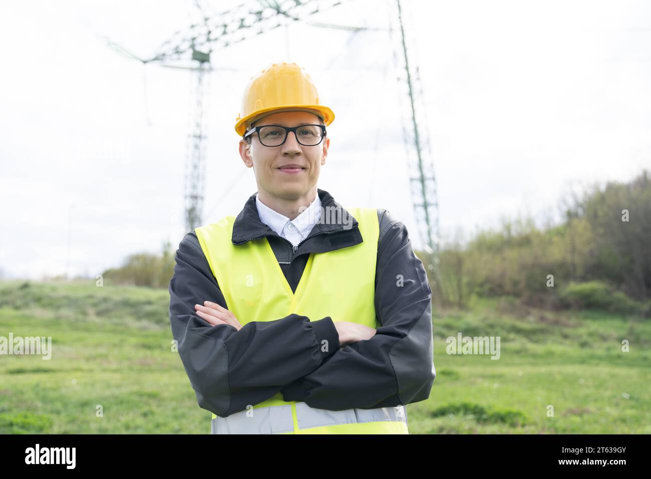 Progettare con un tablet digitale sullo sfondo di una torre della linea elettrica. Foto Stock