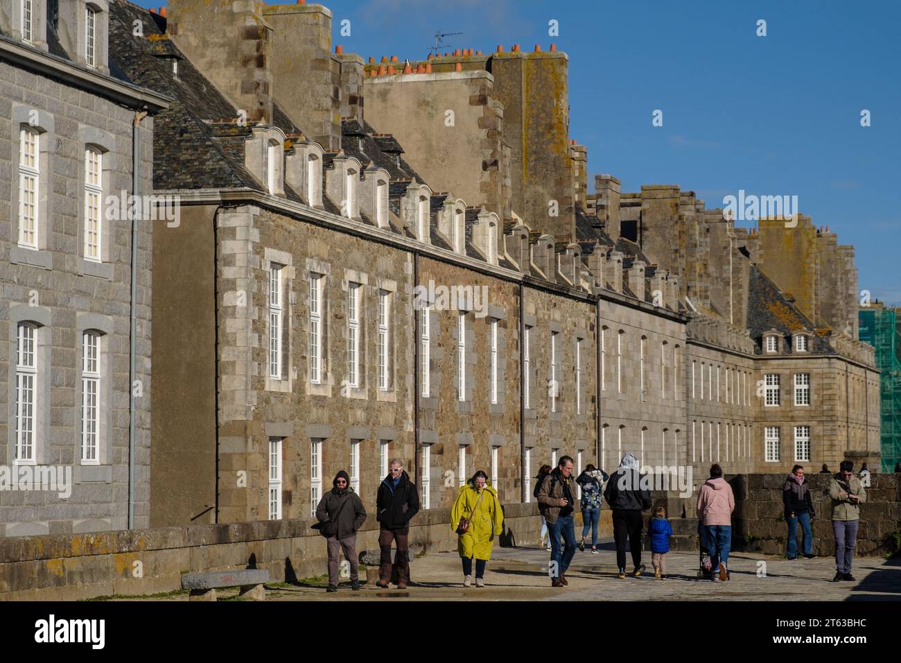 Gente sui bastioni meridionali di St Malo in autunno con l'architettura di intra muros sullo sfondo Foto Stock